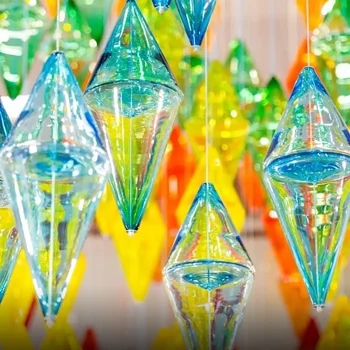 Colorful glass orbs and cones hang closely together, reflecting light in blue, green, and yellow hues.