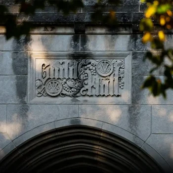 Stone sign reading "Smith Hall" above an arched entrance, with tree branches and sunlight in the foreground.