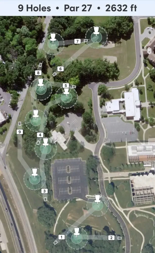 Aerial map of a 9-hole disc golf course designed for outdoor recreation, with fairways and baskets marked, surrounded by trees and buildings.