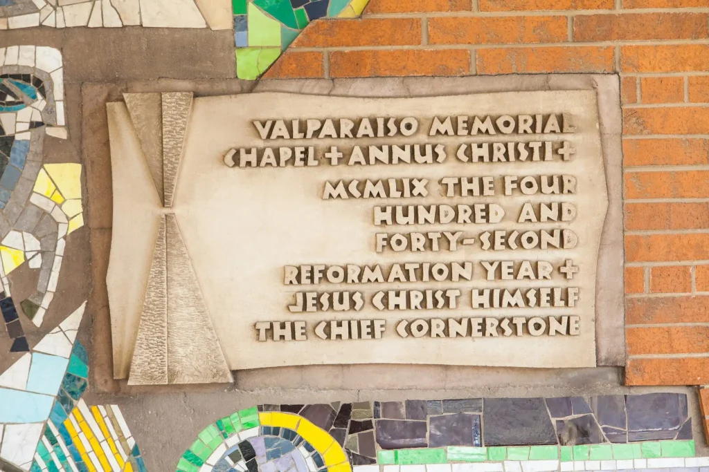 Stone plaque on a brick wall with engraved dedication text, commemorating the rich Chapel history of Valparaiso Memorial Chapel.