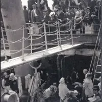 Black and white photo of immigrants crowded on a ship’s deck, some standing, some walking below—part of our powerful Exhibitions & Series exploring journeys and new beginnings.