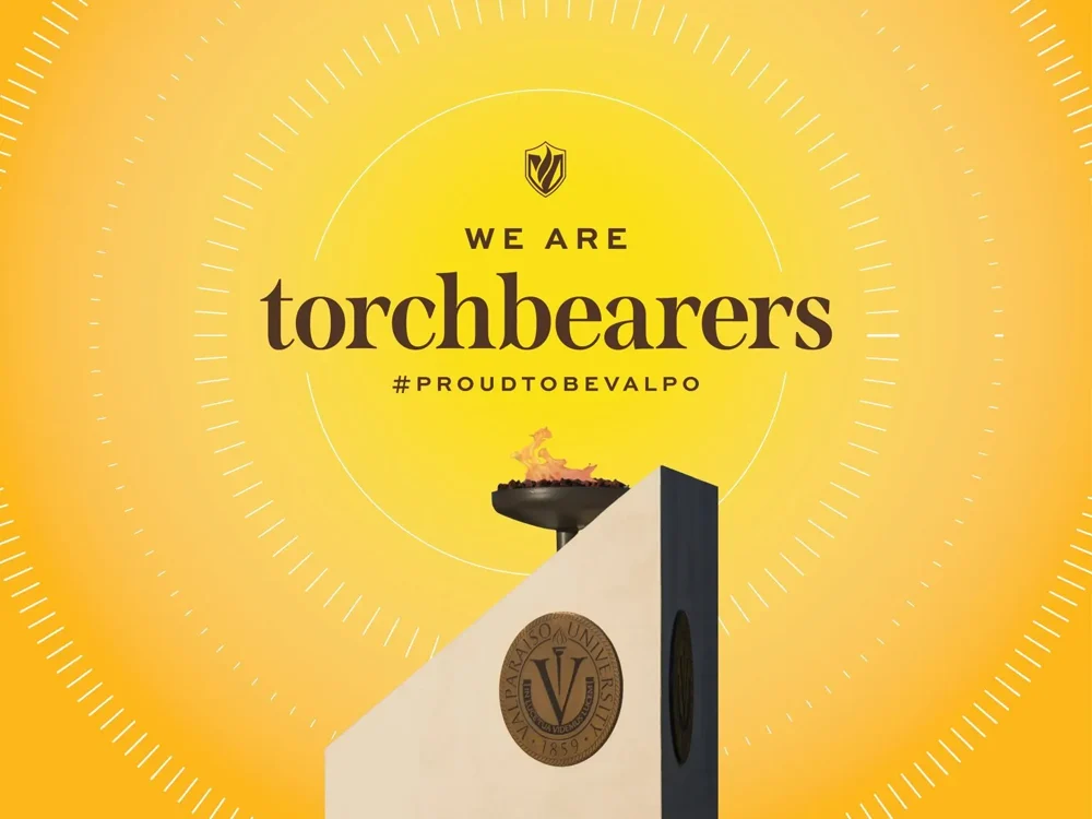 Valparaiso University torch with flames and text: "We are torchbearers #ProudToBeValpo" on yellow background.