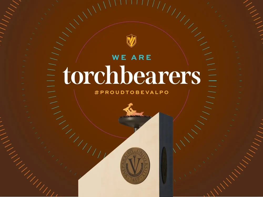 Valparaiso torchbearer monument with text: "We are torchbearers #ProudToBeValpo" on a brown background.