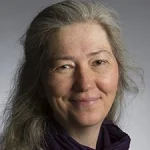 Laurie S. Eberhardt, a middle-aged woman with long gray hair, smiles softly at the camera while wearing a dark scarf.