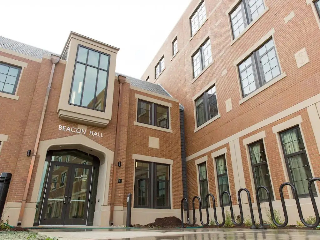 The entrance to Beacon Hall features glass doors and convenient bike racks just outside, welcoming visitors into the brick building.