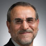 Smiling middle-aged man with glasses, grey beard, and short hair, wearing a suit jacket. Zuhdi Aljobeh, Ph.D.