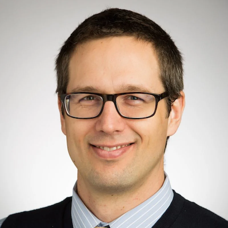 Smiling man with short brown hair, glasses, and wearing a collared shirt and sweater—Christopher Iceman, Ph.D.
