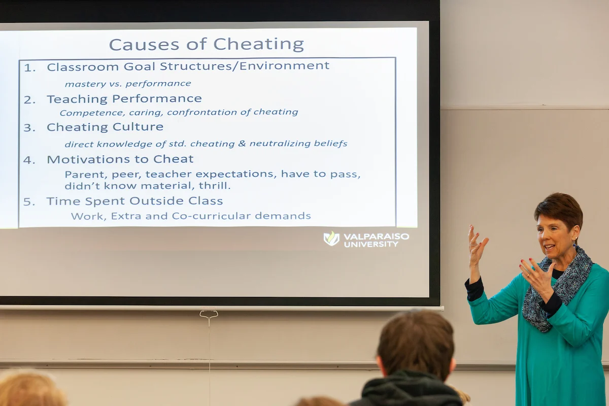 A woman lectures in front of a screen listing causes of cheating and discusses Academic Policies at Valparaiso University.