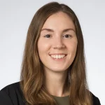 Lauren Sestito, Ph.D., a young woman with long brown hair, smiles at the camera against a plain light background.