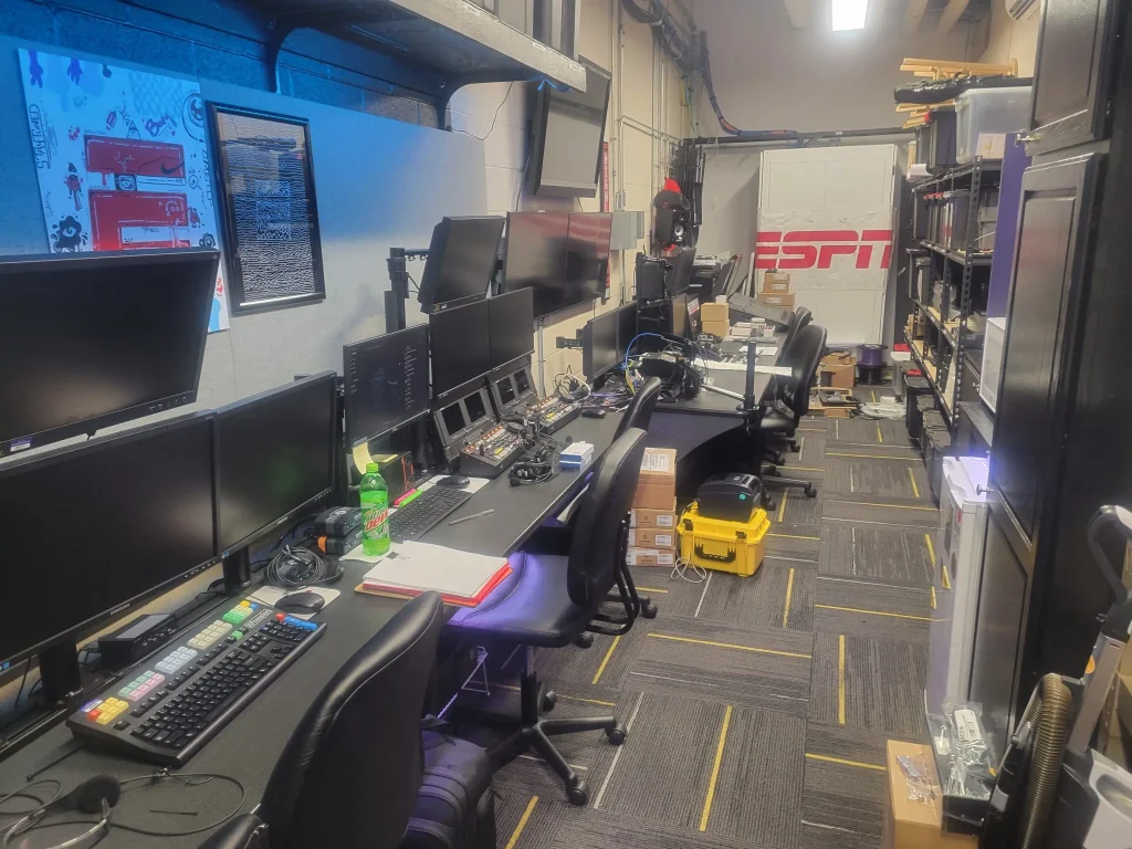 A broadcast control room with multiple monitors, keyboards, equipment, and an ESPN Valparaiso University Productions sign in the background.