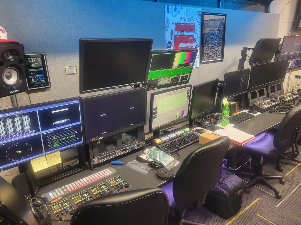 A broadcast control room for ESPN Valparaiso University Productions, featuring multiple monitors, control panels, and equipment on desks.