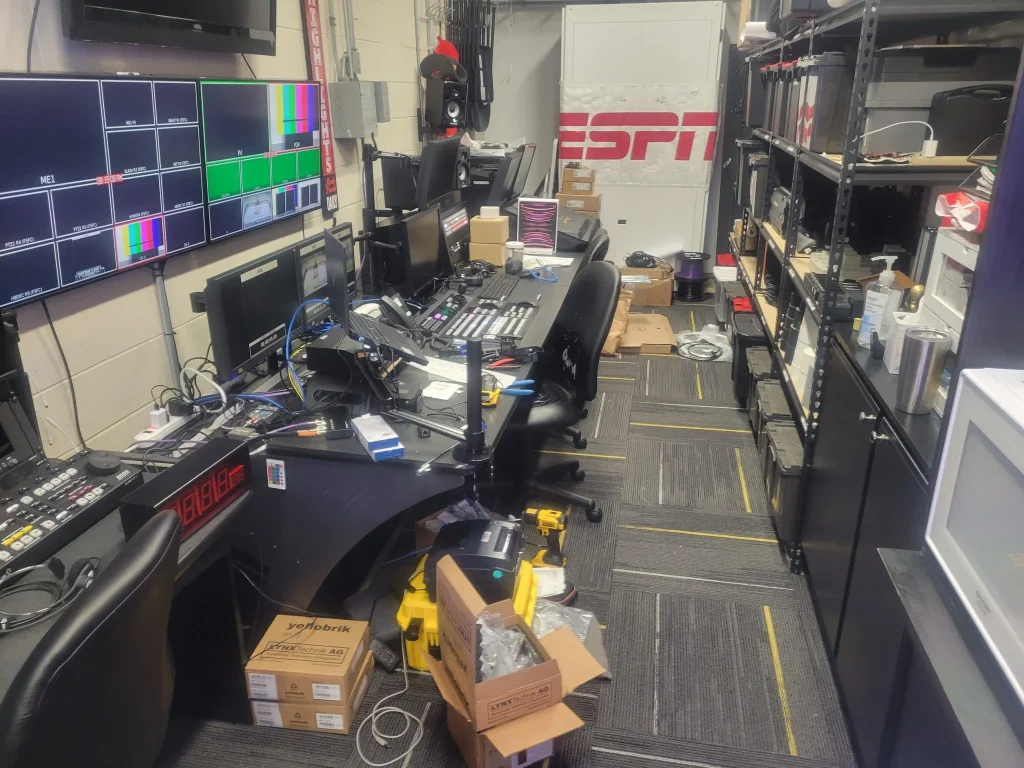 Broadcast control room with multiple monitors, equipment, and boxes; ESPN Valparaiso University Productions sign visible in the background.