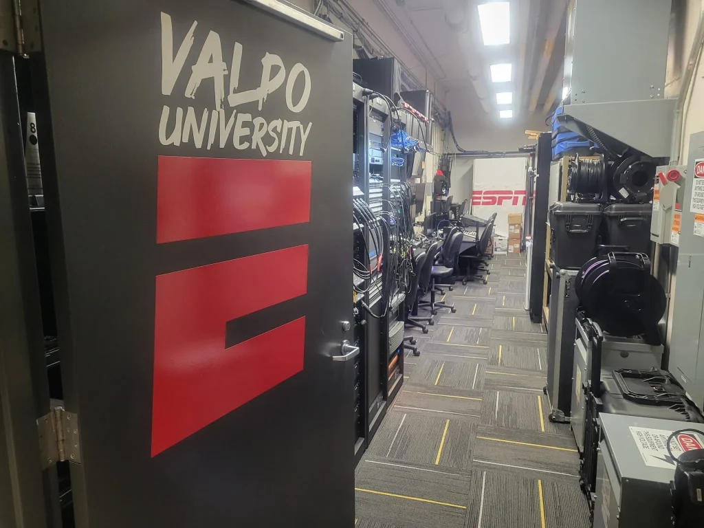 A door with "Valpo University" leads to a room filled with cables, equipment, and an ESPN Valparaiso University Productions banner in back.