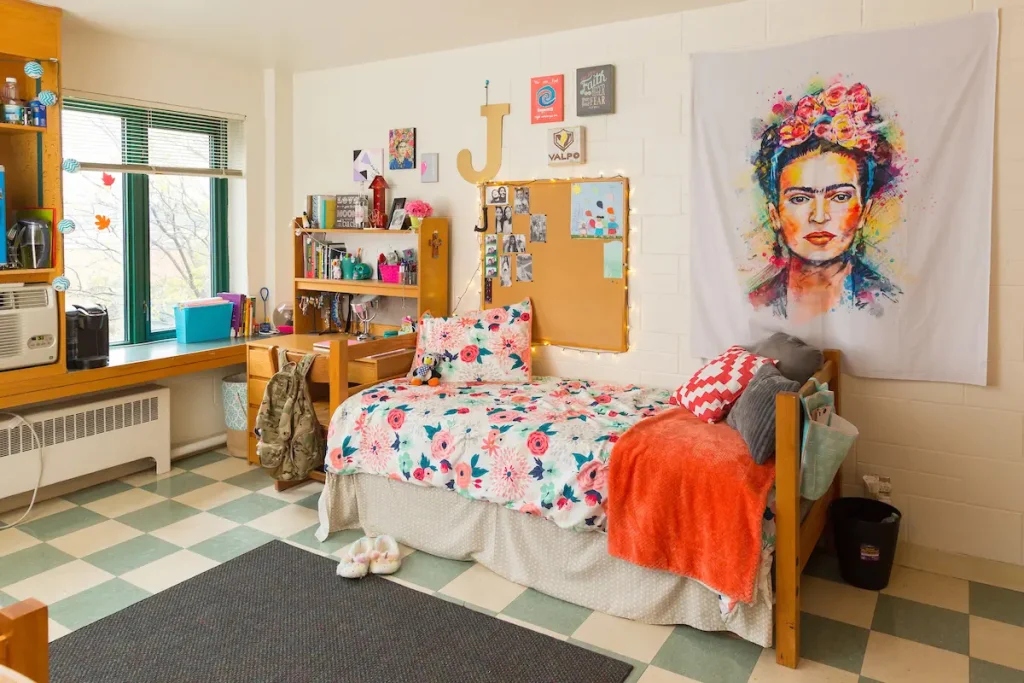 Colorful dorm room with a single bed, floral bedding, desk, shelves, and vibrant Frida Kahlo wall art—perfect for students seeking stylish Off-Campus Housings.