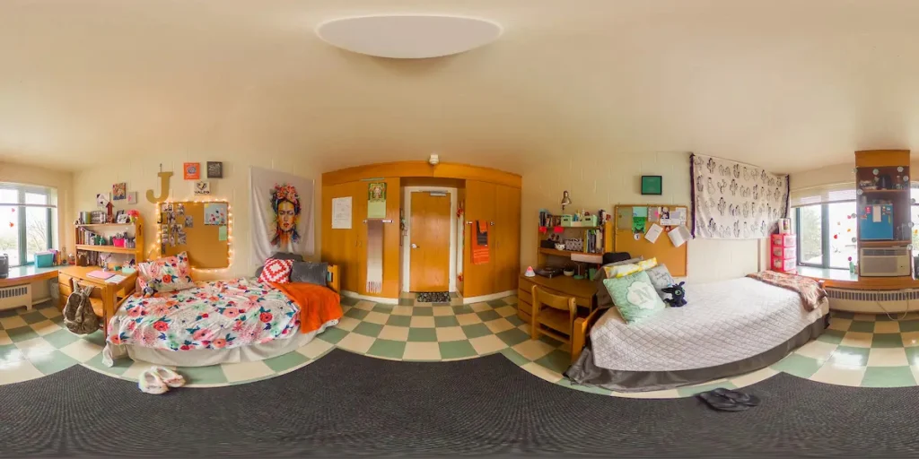 A bright dorm room with two beds, desks, colorful decor, and large windows letting in natural light—perfect for students seeking Off-Campus Housings with a vibrant and welcoming atmosphere.