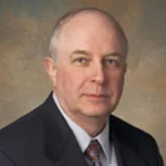 A middle-aged man in a suit and tie, reminiscent of Gilbert Meilaender, Ph.D., poses for a professional headshot against a neutral background.