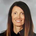 Bridget Murphy, a smiling woman with long brown hair, wears a black top against a gray background.