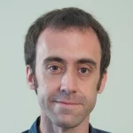 Alberto López Martín, a man with short brown hair and sideburns, wearing a dark shirt, smiles slightly at the camera.