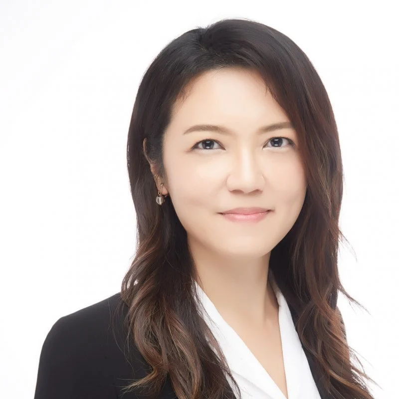 Professional woman with long brown hair, PhD holder Yi-Ju Chien, wearing a black blazer and white blouse, smiling at the camera.