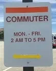 White parking sign reading "COMMUTER MON.-FRI. 2 AM TO 5 PM" with a yellow arrow pointing right at the bottom.