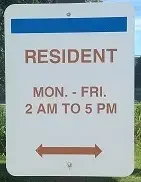 White parking sign reads "RESIDENT MON.-FRI. 2 AM TO 5 PM" with a double-headed arrow at the bottom.