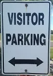 A "Visitor Parking" sign featuring a double-headed arrow beneath the text indicates available parking in both directions.
