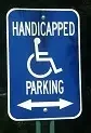 Blue handicapped parking sign featuring a wheelchair symbol and arrows pointing left and right to indicate accessible parking directions.