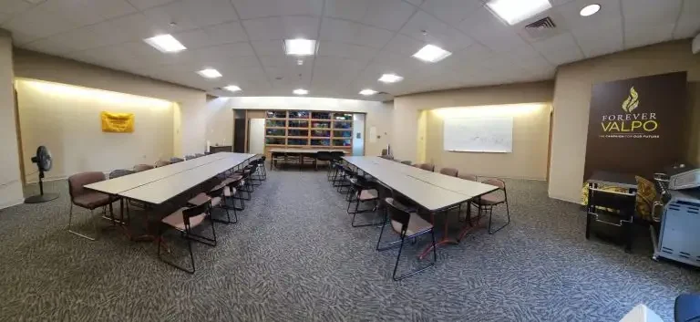 A conference room in Loke Hall with U-shaped tables, chairs, shelves in back, and a "Forever Valpo" sign on the right wall.