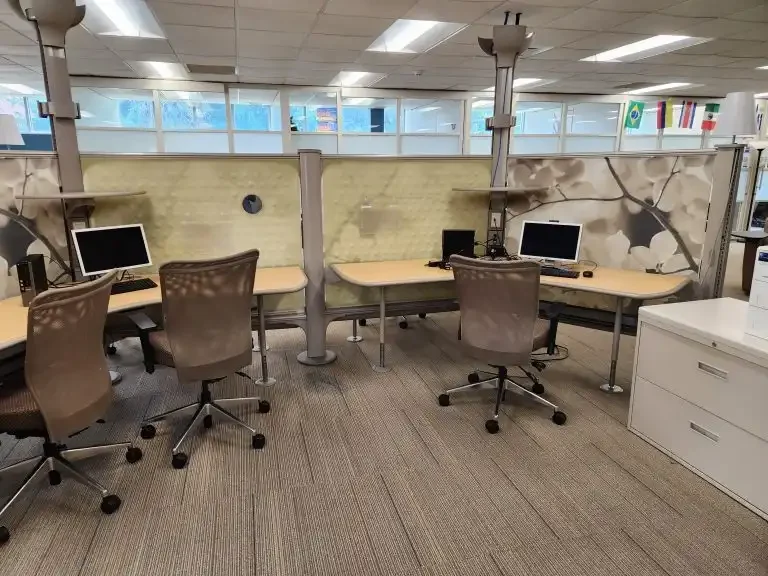Three empty office cubicles with computers, chairs, and partition walls create a modern workspace in Loke Hall.